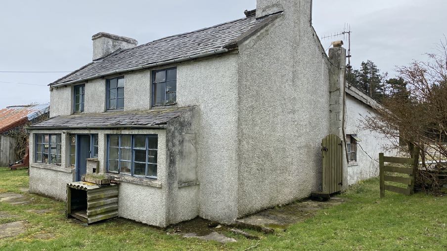 A photograph of the existing two-story detached house proposed for demolition, featuring roughcast rendering and a single-story extension on the front elevation.