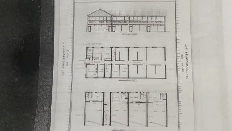 This image displays an architectural drawing featuring a floor plan and elevations for a long, narrow building structure, labeled as an office, cabin, or yurt.
