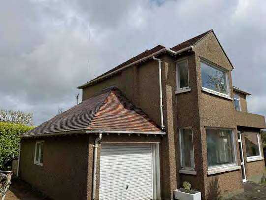 A photograph of a two-story detached house with brown pebbledash cladding and an attached garage with a white roller door.