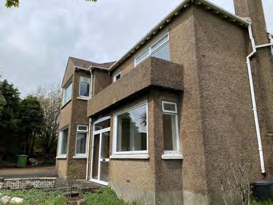 A photograph showing the exterior of an existing two-storey detached house with pebbledash rendering and large windows.