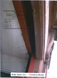 A close-up photograph showing the channel and shutter mechanism of a roller shutter, with a label at the bottom identifying it as 'Roller Shutter No 1'.