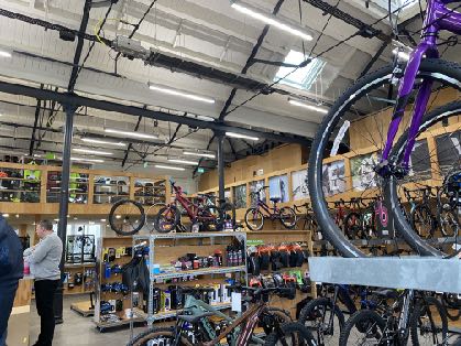 Interior photograph of a bicycle shop with bikes hanging from the ceiling and customers browsing.