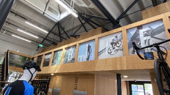 Interior photograph of a commercial space featuring wooden paneling, cycling-themed artwork, and bicycle displays.