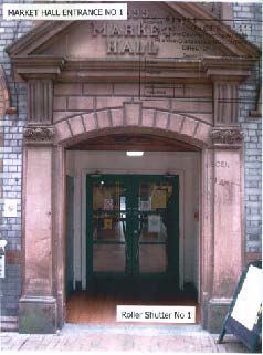 A photograph showing the stone entrance archway of the Market Hall in Braddan, dated 1899. The image displays the doorway with glass doors and a sign on the pavement.