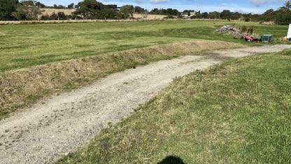 A photograph showing a grassy field with a gravel track running through it, depicting the existing site conditions.