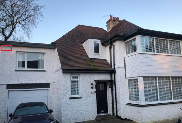 A photograph showing the front exterior of a white, two-story detached house with a garage on the left and a car parked in the driveway.
