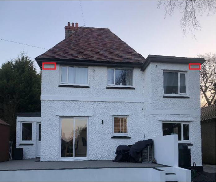A photograph showing the exterior elevation of a two-story white detached house with a tiled roof and a patio area.