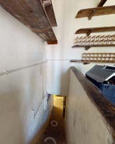 Interior view of a building showing exposed wooden ceiling beams and white walls, likely during renovation or restoration works.