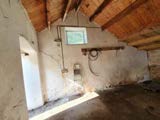 Interior photograph of a room with exposed timber roof rafters and a small window, likely an attic space undergoing restoration.