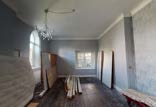A photograph showing the interior of a room undergoing renovation with exposed walls, wooden floors, and a chandelier.