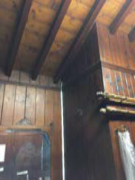 Interior photograph of a room featuring exposed wooden ceiling beams and wooden wall paneling.