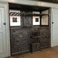 An interior photograph showing a large, dark cast-iron range cooker built into wooden cabinetry with framed items on shelves above.