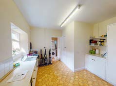 Interior photograph of a kitchen or utility room featuring white cabinetry, a window, and patterned yellow flooring.
