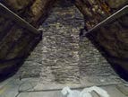A close-up photograph showing the rough stone masonry of a gable end or chimney stack, likely part of an older rural building.