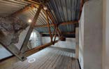 Interior photograph of a loft conversion space featuring exposed wooden roof trusses and corrugated metal roofing.