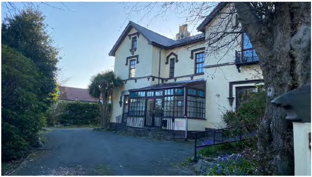 A photograph of a two-story detached house featuring a large glass conservatory extension and a driveway.