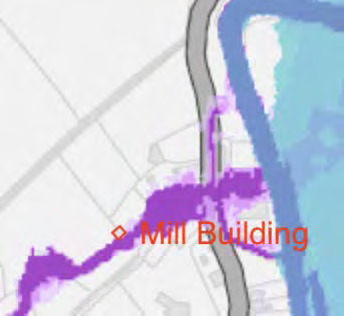 A digital map showing the location of the 'Mill Building' adjacent to a road and a body of water, with purple shaded areas indicating specific zones.