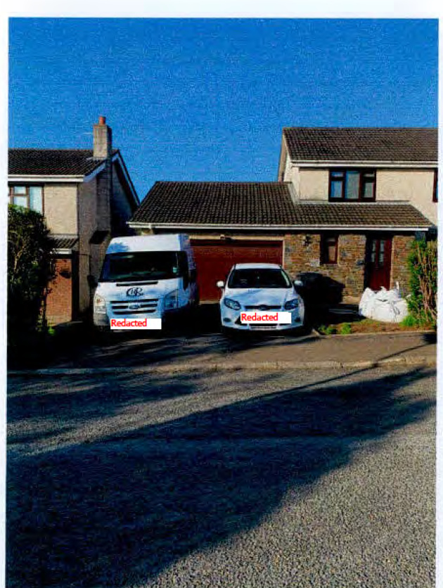 A photograph showing a detached house with a driveway where a white van and car are parked.