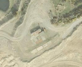 Aerial view of a former quarry site showing a small building, access tracks, and surrounding vegetation.