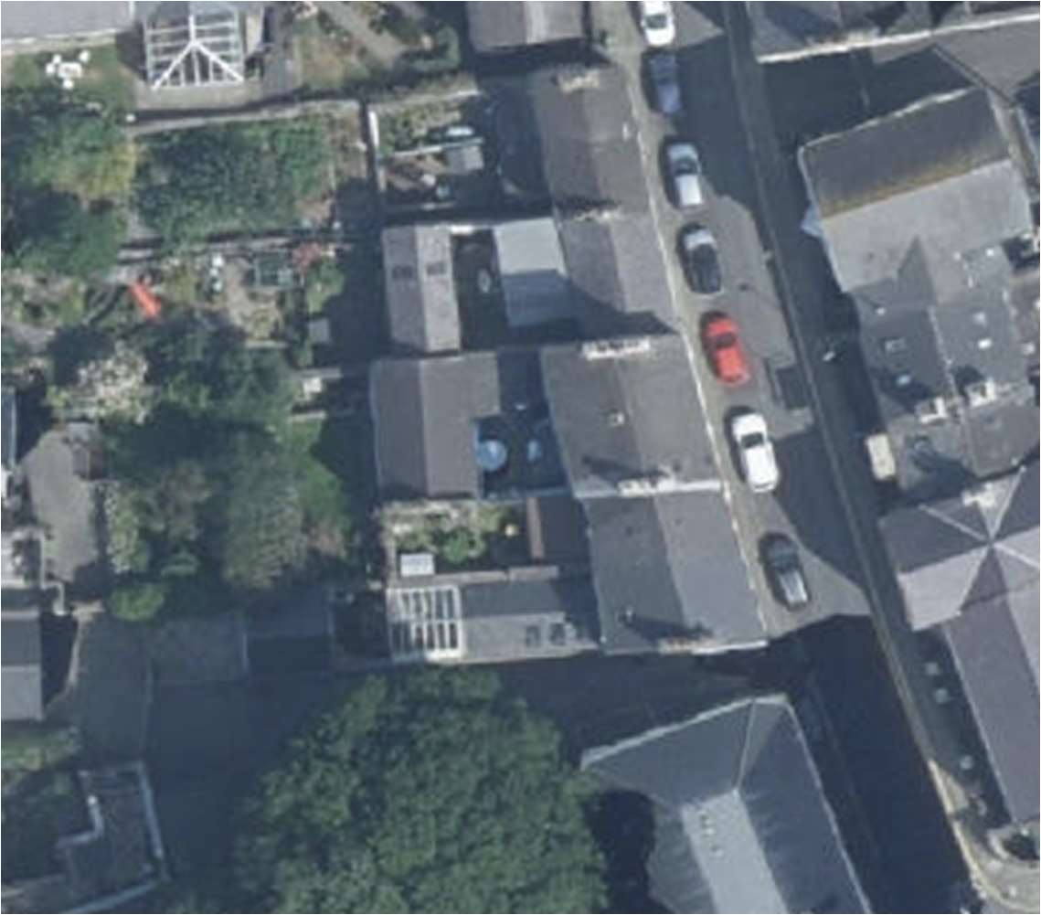 An aerial satellite view showing a row of terraced houses with rear gardens and cars parked along the street.