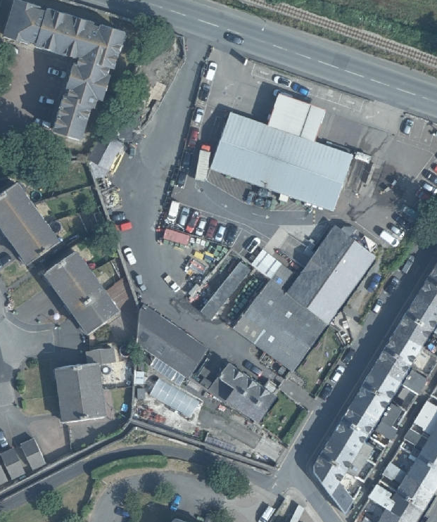An aerial view of the Commissioners Yard site showing industrial buildings, parking areas, and surrounding residential properties.