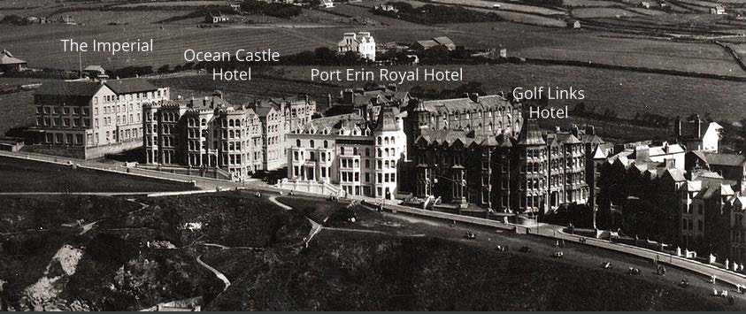 A black and white photograph showing a row of large historic hotels along a coastal road, with text labels identifying buildings like the Ocean Castle Hotel and Port Erin Royal Hotel.