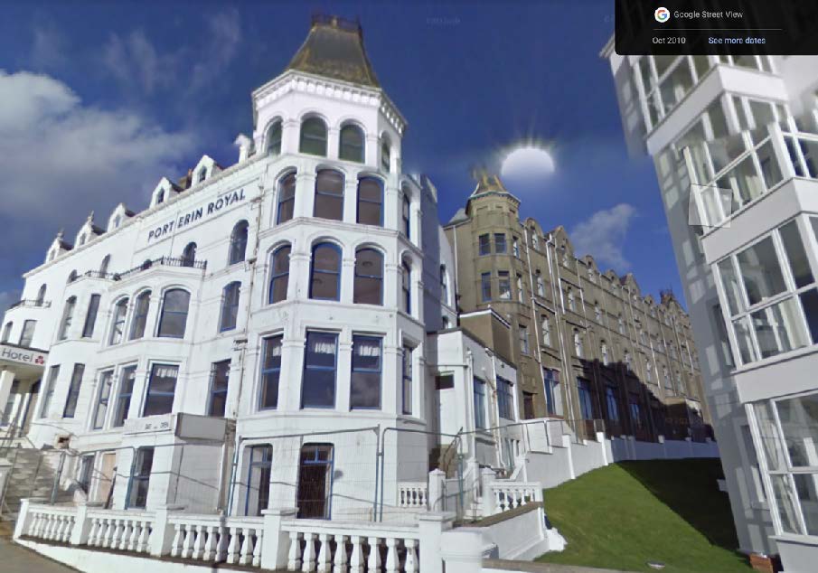 A Google Street View photograph showing the exterior of the large white 'Port Erin Royal' building, likely a hotel, situated on a slope with a grassy bank and white boundary walls in the foreground.