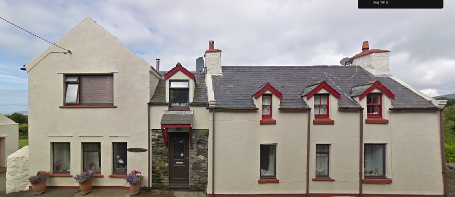 A photograph showing the exterior elevation of a large white-washed residential property with a slate roof and red window trim.
