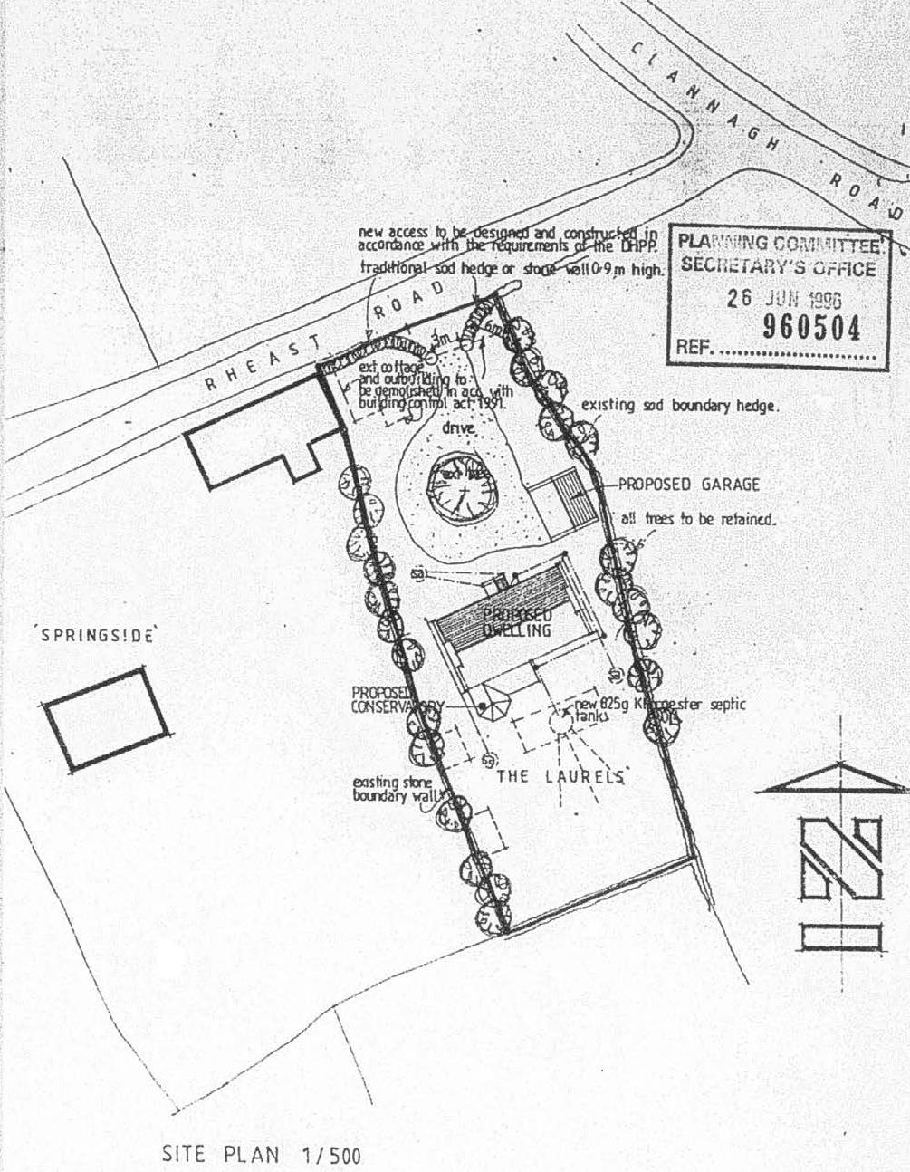 A 1/500 scale site plan showing the layout for a proposed detached dwelling, garage, and driveway on a plot fronting Rheast Road, stamped by the Planning Committee Secretary's Office in 1996.