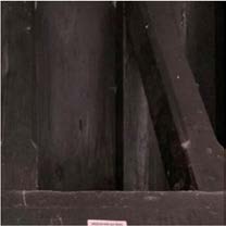 Close-up photograph showing dark, historic timber roof beams and structural framing details.