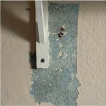 A close-up photograph of a wall surface showing a patch of blue material and a white vertical fixture, likely documenting a detail for the proposed restoration works.
