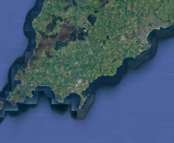 An aerial satellite view showing a green, rural coastal landscape with fields and water bodies.