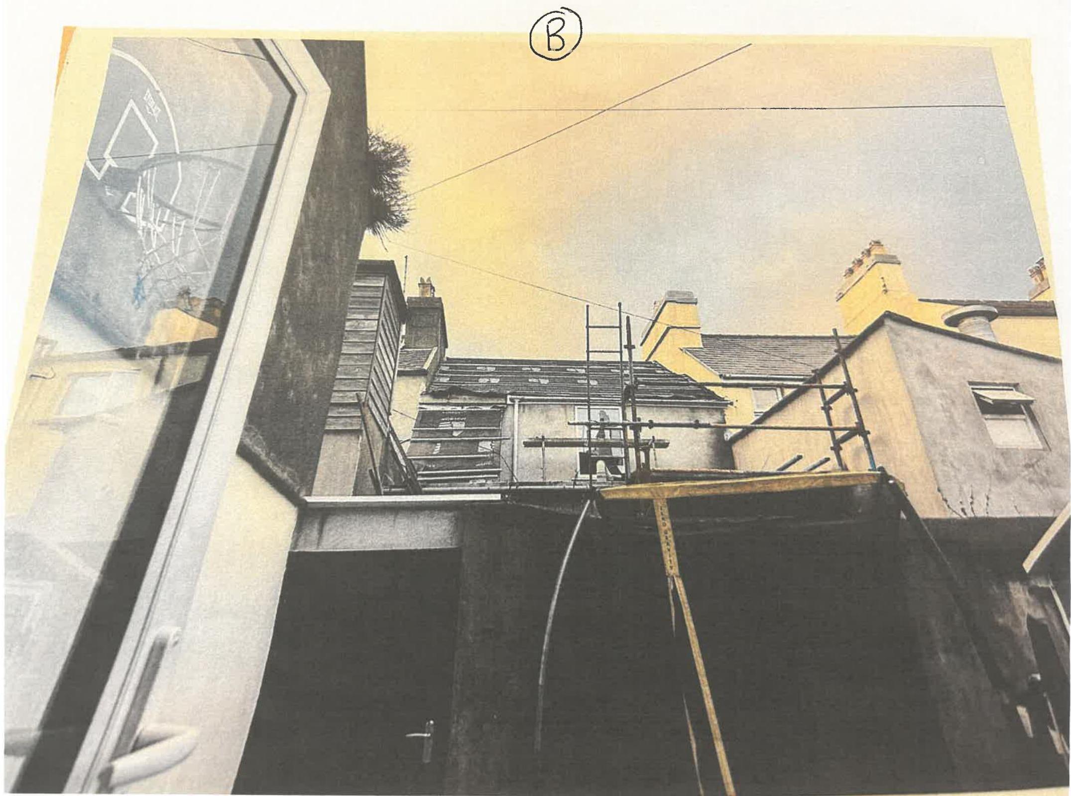 A photograph showing a view looking up at the side of a building with scaffolding erected against the wall.