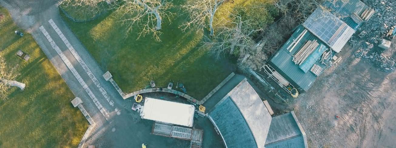 Aerial photograph of a property showing a driveway with paving blocks, a lawn, and a shed with solar panels.