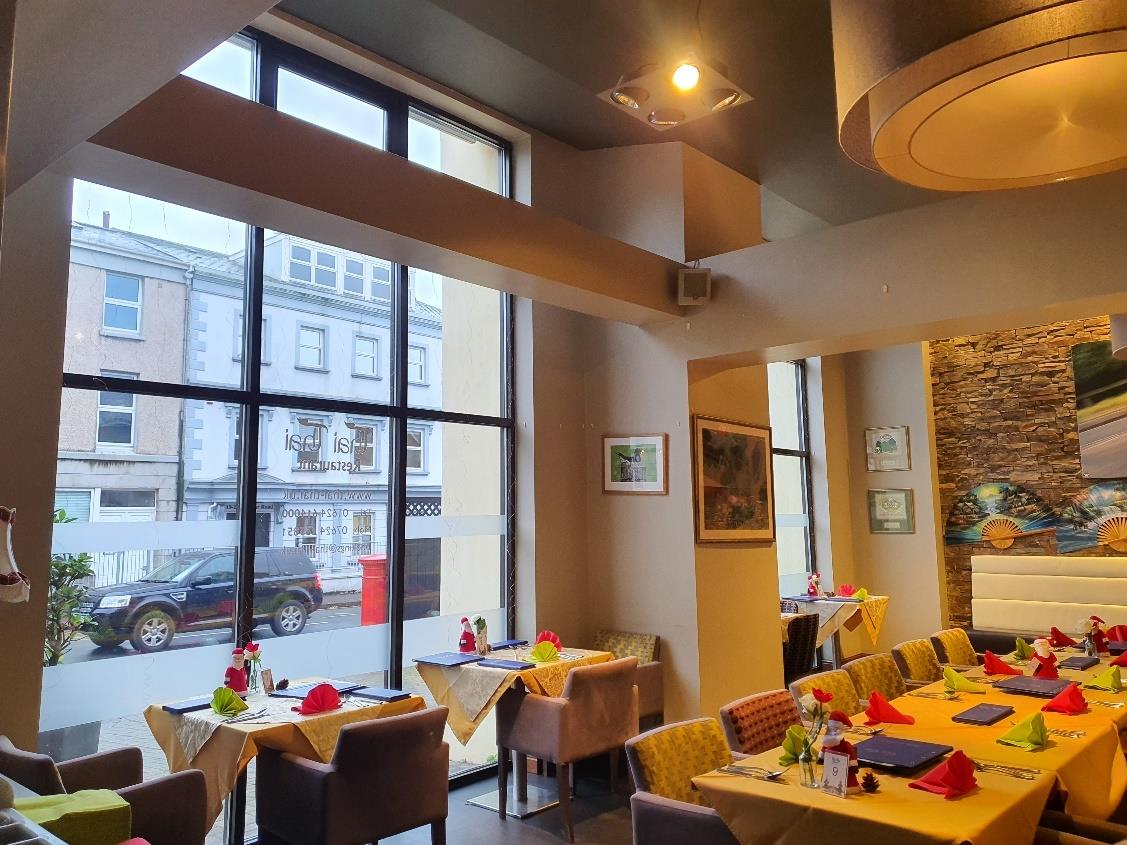 Interior photograph of a restaurant or café with tables set for dining and large windows overlooking a street.
