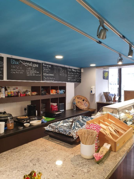 Interior photograph of a cafe or restaurant counter area featuring menu boards and service equipment.