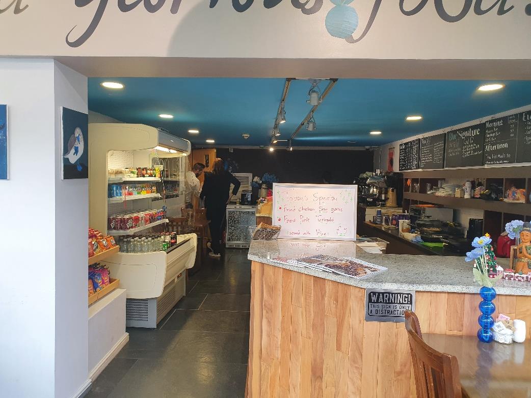 Interior photograph of a cafe or restaurant showing the service counter, menu boards, and refrigerated display units.