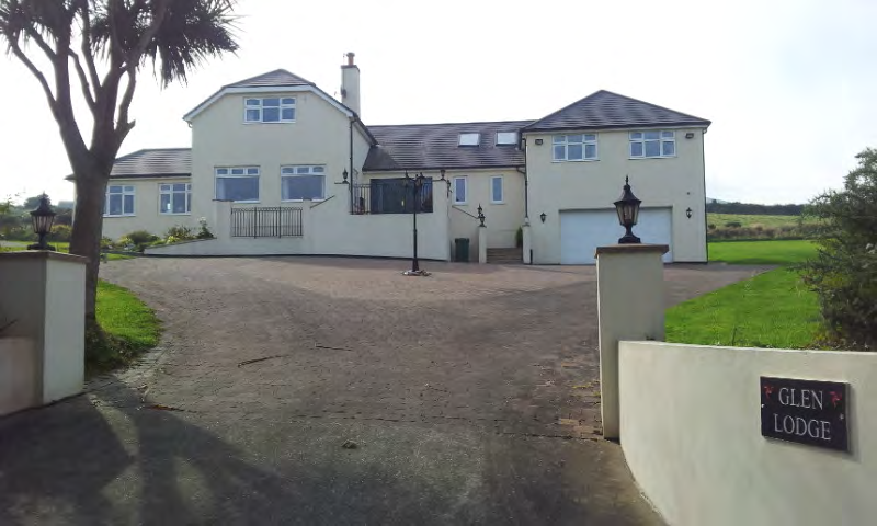 A photograph showing a large detached cream-colored house named 'Glen Lodge' with a wide driveway and rural surroundings.