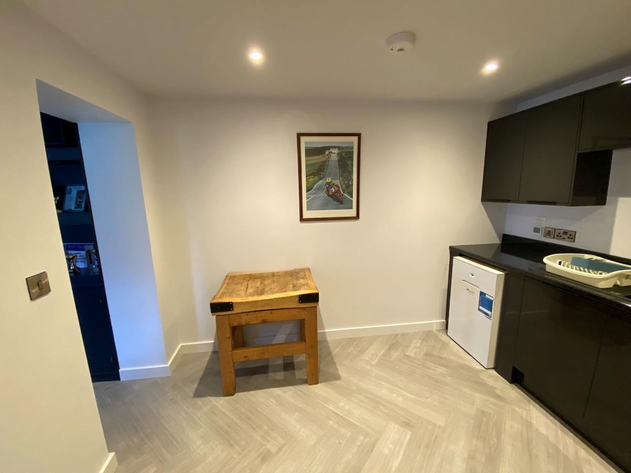 Interior photograph showing a modern kitchen area with dark cabinetry and herringbone flooring, representing the finished conversion of the agricultural building.