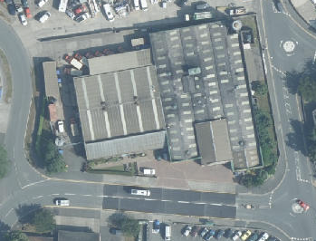 An aerial view of a commercial industrial site showing two large units with parking areas and surrounding roads.