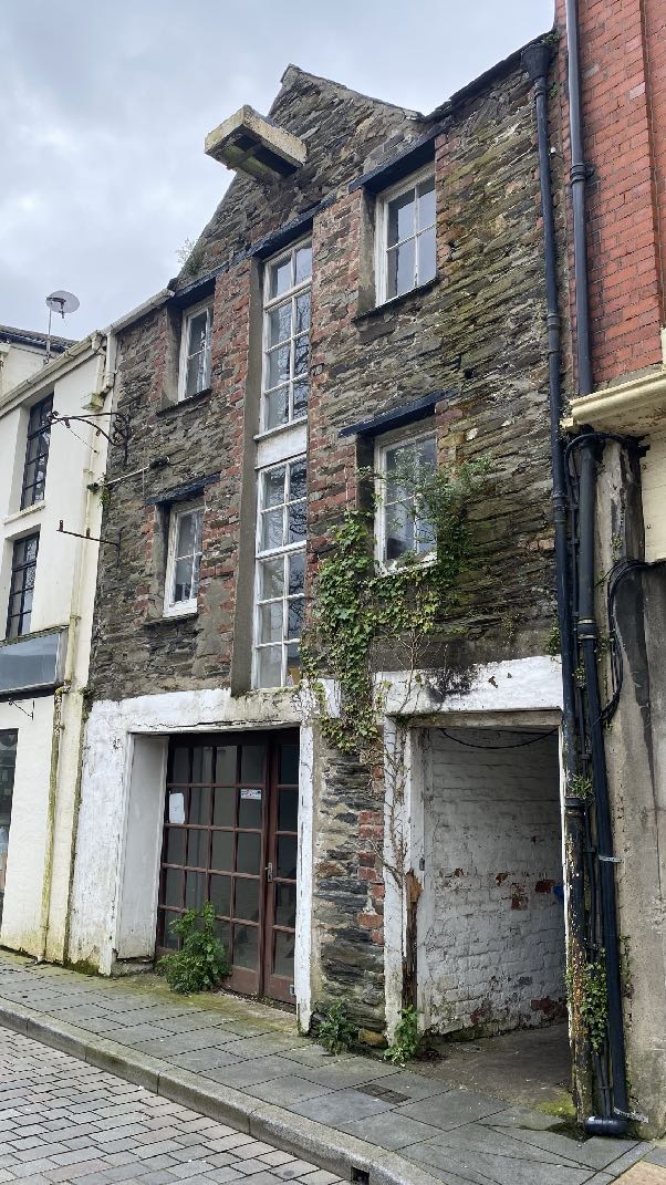 A street-level photograph showing the front elevation of a multi-story stone building with sash windows and a ground floor entrance.