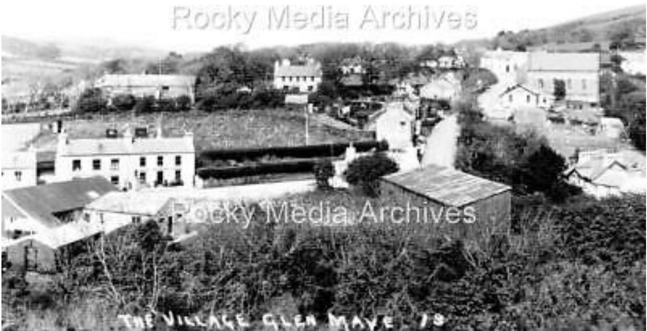 A black and white historical photograph showing a rural village scene with houses and fields, labeled 'The Village Glen Maye '19'.
