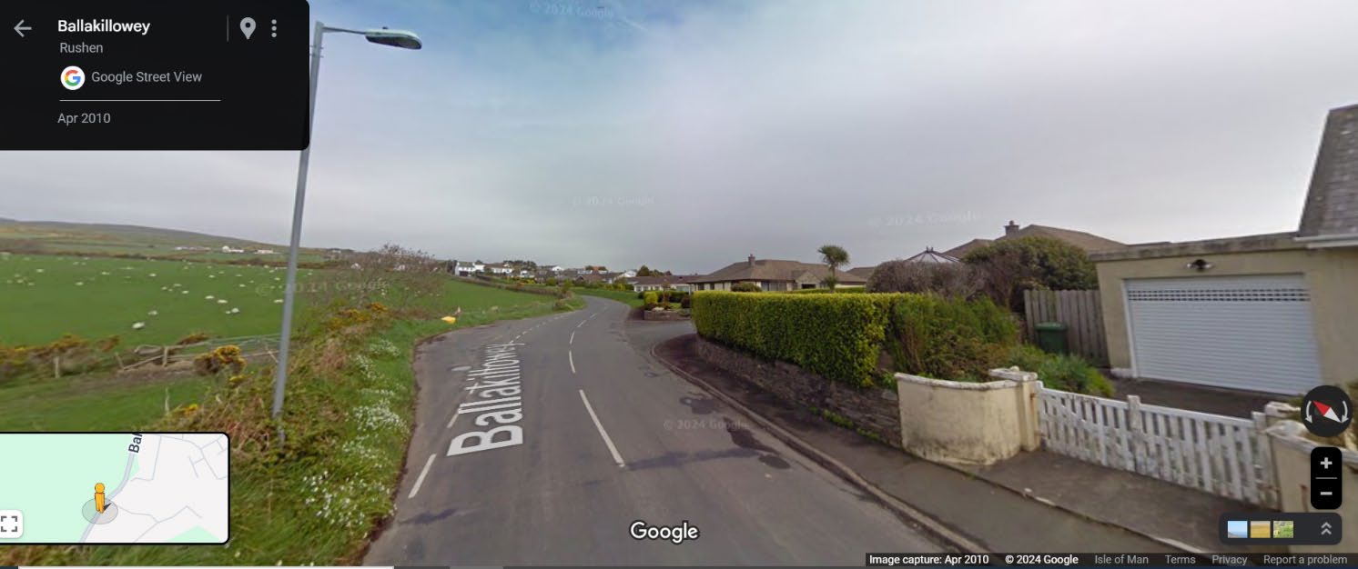 A Google Street View screenshot showing the road Ballakilley in Rushen, featuring a house with a garage on the right and green fields with sheep on the left.