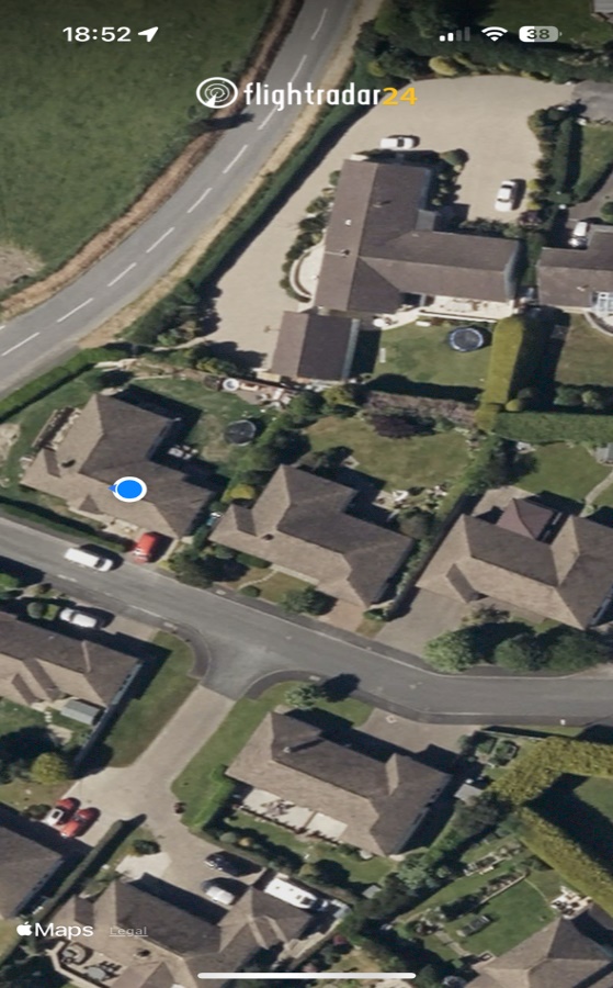 Aerial satellite map view showing a residential property marked with a blue dot, surrounded by roads and neighboring houses.