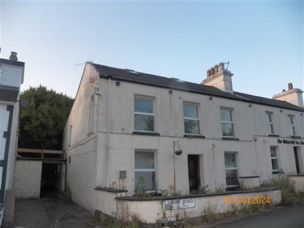A photograph of a two-story white rendered building on Shore Road, appearing to be a former inn or commercial property with a low boundary wall.