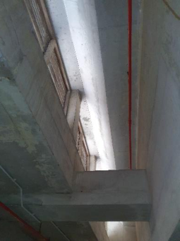 Interior photograph of a building under construction showing concrete beams, columns, and formwork with a red pipe running vertically.