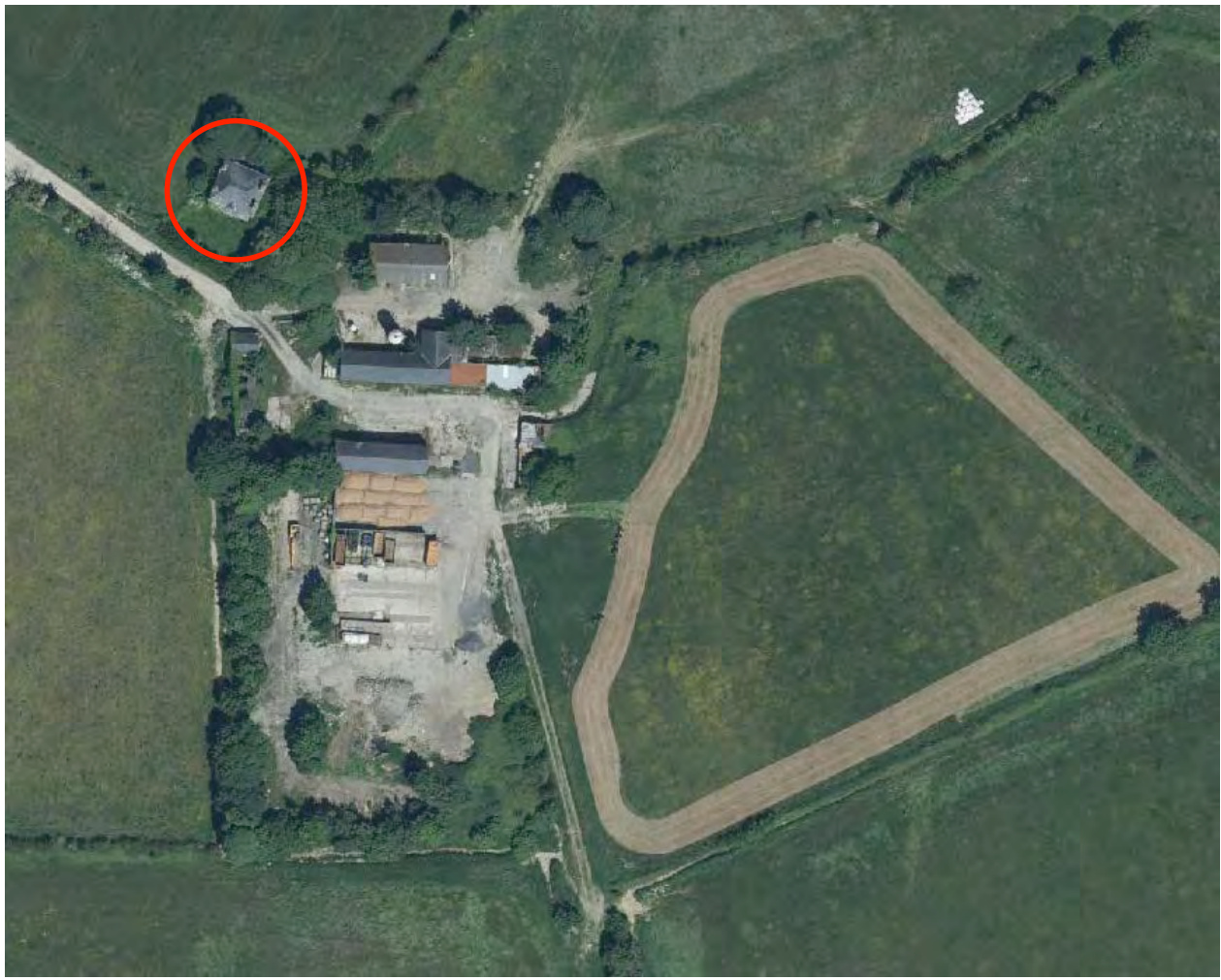 An aerial view showing a rural property with a cluster of buildings and a track, with a specific building highlighted by a red circle.