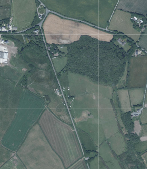 An aerial view of a rural landscape showing fields, hedgerows, and a road, serving as a site location map for the proposed development.
