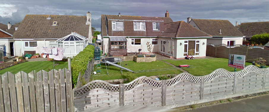 A street-level photograph showing a detached bungalow with a rear conservatory and side extension, surrounded by gardens and wooden fences.