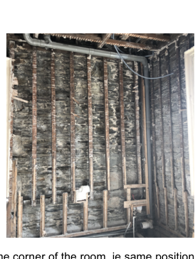 Interior photograph showing a stone wall with wooden battens and a newly installed downpipe.